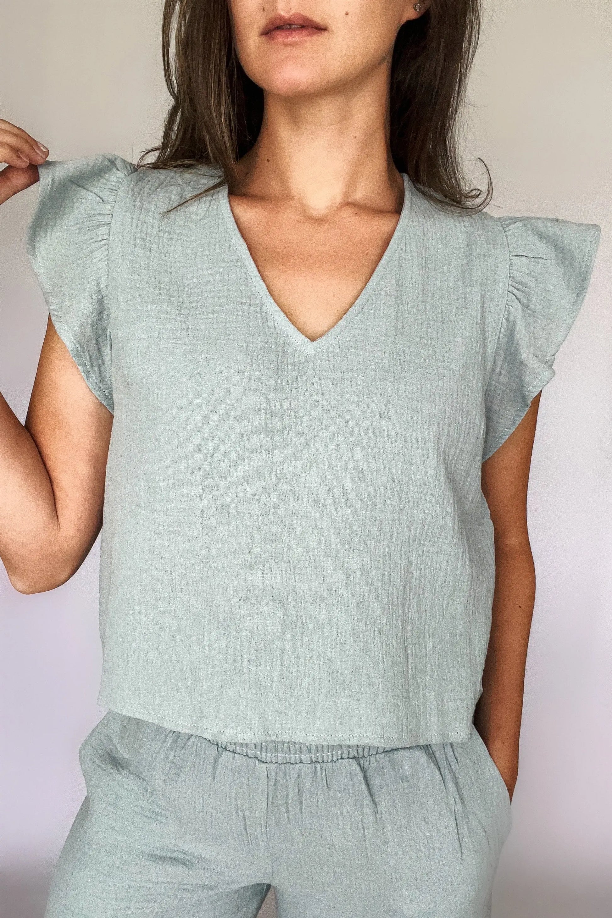 A woman modeling a sea blue cotton gauze ruffled sleeve top with matching pants