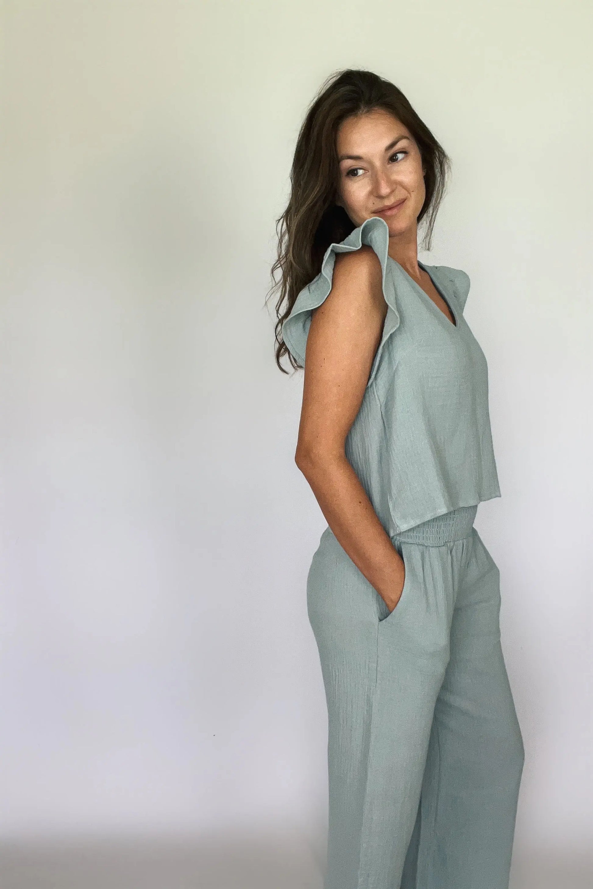 A woman modeling a sea blue cotton gauze ruffled sleeve top with matching pants