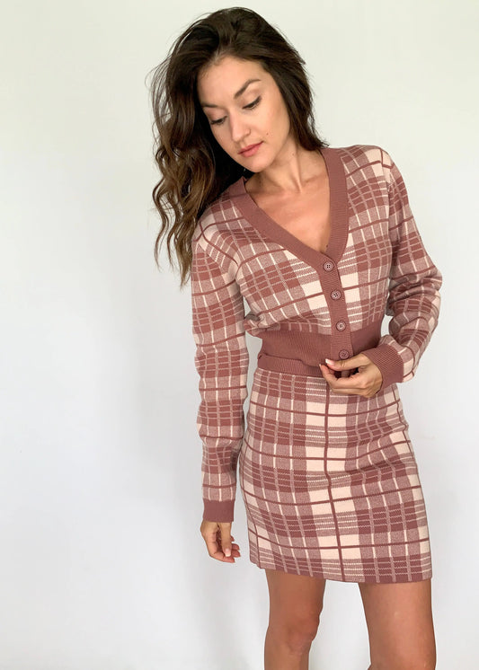 A model wearing a mauve plaid v-neck cropped cardigan with matching skirt