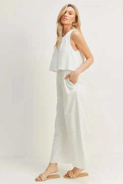 A woman modeling a white wide-leg sleeveless jumpsuit