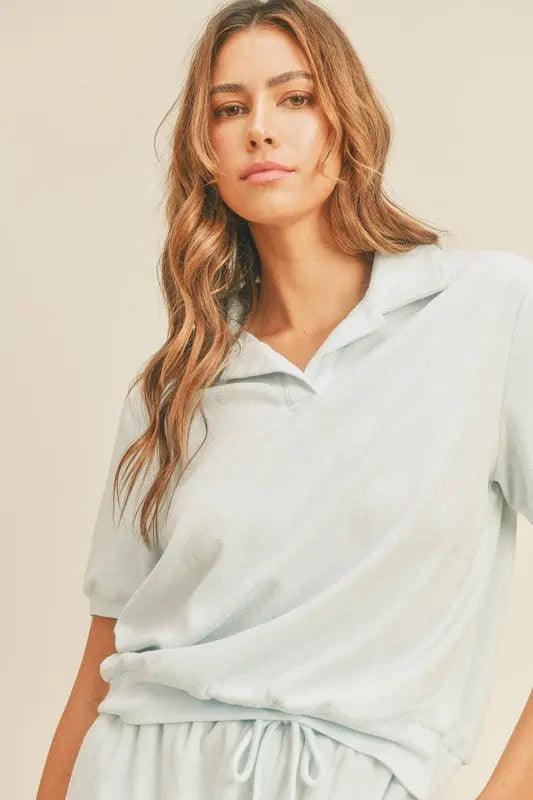 A female model wearing open collar polo and short terry cloth set