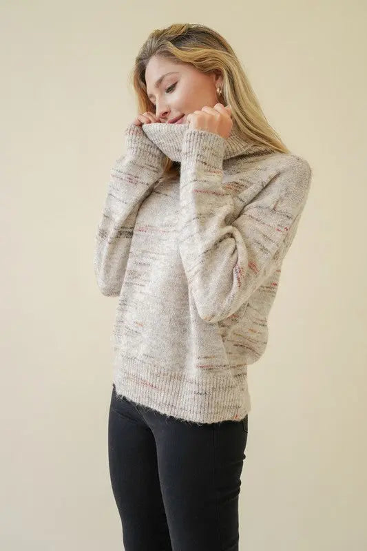 A female model showcasing a oatmeal textured turtleneck pullover sweater